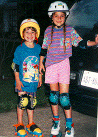 Two young in-line skaters wearing colorful protective gear.