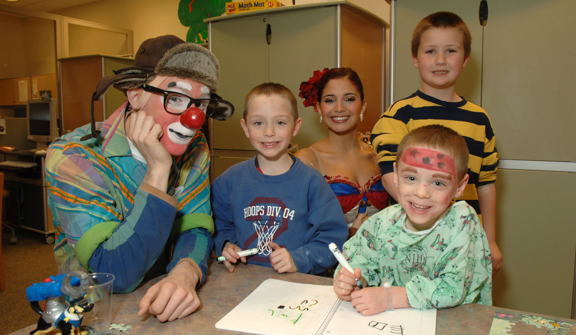 From left, clown Skoy; Joshua Jeffes; dancer Figuereido; Bennett Hume; and Jarrod Jeffes (patient with face paint) share a look at the kids’ artwork.