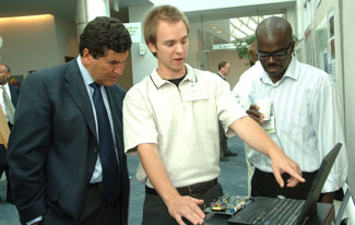 NIH director Dr. Elias Zerhouni (l) hears from Stanford Uni-versity postdoctoral researcher Dr. John Arthur (c) about Neurogrid, a bioengineering approach to emulating the way neurons compute that is being pursued by 2006 Pioneer Award recipient Dr. Kwabena Boahen (r) of Stanford.