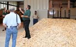 Dr. Les Groom explains the energy conversion process of the gasification unit while standing on a pile of wood chips (biomass).