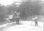 1914 photo of a soil survey depicts two soil scientists at a road corner reading the odometer, taking the sight, and measuring distance and direction.  (NRCS image — click to enlarge)