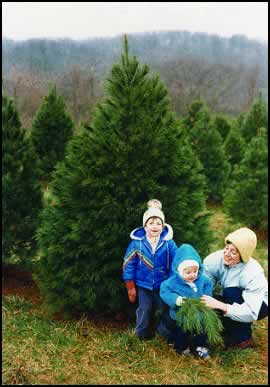 Photograph of a family in front of pine trees.