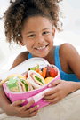 Image of a little girl showing a lunch box full of nutritious foods
