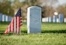 A tomb at a cemetery with an American flag next to it.