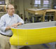 Prof. Michael Parsons of the U-M Naval Architecture and Marine Engineering department leans against a scale model used to test the revolutionary U-M ballast-free ship design