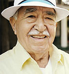 An older man wearing a white hat, smiling.