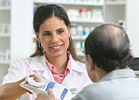 A pharmacist handing medications to a man.