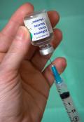 Photo shows a hand holding a vaccine vial and a syringe