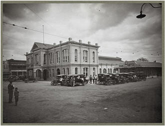 Main street de la pequeña ciudad con autos aparcados en la plazoleta. c.1920-1930.