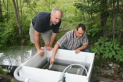 Photo: ARS agricultural engineer Kevin King (right) and Spectrum Research, Inc., soil scientist Jim Balogh inspect a filter cartridge system attached to a golf course tile drain. Link to photo information