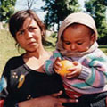Photo of a woman holding her baby and singing hymns (click to learn more about the PEPFAR New Partners Initiative)