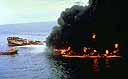 Ship partially on fire with smaller boat spraying water