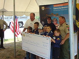 Scout leaders and scouts holding up a large mockup of a check they made out to Jordan NFH
