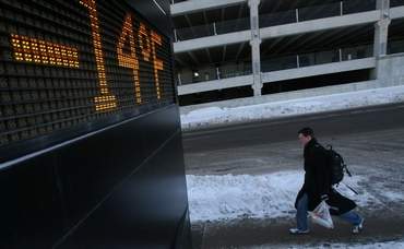 A man makes his way along 7th Street in downtown Des Moines on Thursday morning as a bank sign flashes the temperature -14. JUSTIN HAYWORTH / THE REGISTER
