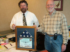 Landscape architect Larry Bean presenting a framed flag and certificate to Assistant Regional Director Don Moomaw in the regional office.