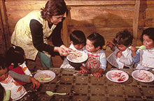 Photo of a Mapuche woman feeding several children at a table.  The Mapuche are a people with a rich history.  As the only South American indigenous culture to not be conquered by the Incas or Spaniards, the Mapuche people maintained a strong presence in Chile until the late 19th century when their lands were overtaken by the government.  Some migrated to the city of Temuco while others, like these children here, remained in the rural "altiplano."  The Professional Society for Rural Development (SOPRODER), in partnership with LWR, has sponsored programs to improve the nutrition and overall living conditions of the Mapuche and preserve their cultural identity.