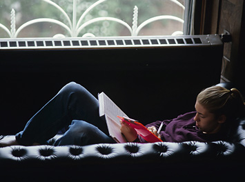 Woman studying on a couch by the window