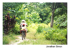 Woman and child riding bicycle through Indonesian forest. Photo Source: Jonathan Simon