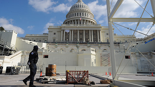 A security guard walks on the west steps of the Capitol