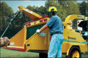 Worker standing next to a chipper.