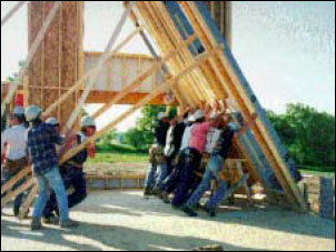 carpenters manually rising a balloon framed wall