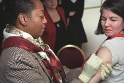 CDC clinician Gloria Brynam (left) demonstrates proper smallpox vaccine application on CDC clinician Melanie King. Photo by James Gathany.