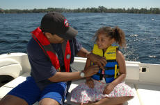 Photograph of a father and daughter on a boat, both wearing life jackets