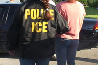 Immigration and Customs Enforcement photo of unidentified ICE officer with unidentified handcuffed suspect in custody