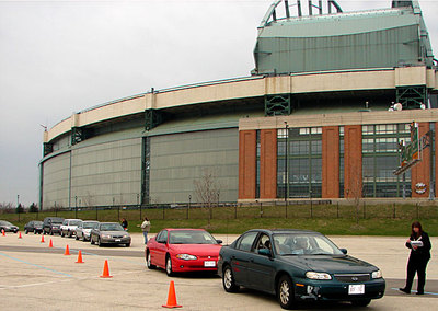 cars lined up outside a sports stadium to drop off medications