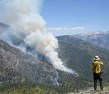 image of man on mountain viewing smoke from a distant fire