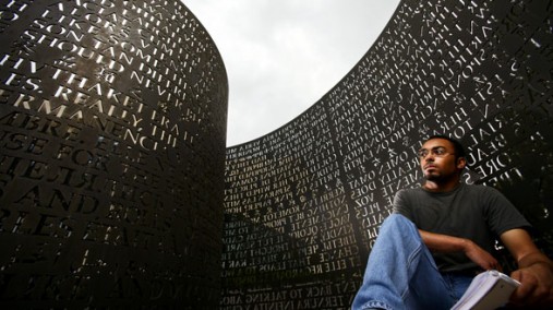 Young man poses in front of a wall engraved with various languages, Houston, TX, Dec. 20, 2008. [AP]