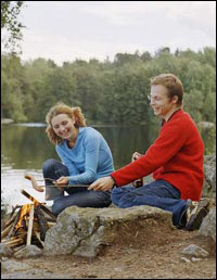 Photo: A couple roasting hotdogs over a campfire