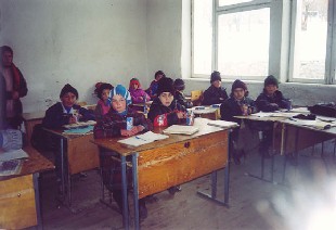 School Children in Tajikistan, bundled up against the cold in their unheated classroom, recieve their USDA-supplied boxes of milk.
