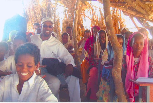 Large group of children in sparsely roofed classroom