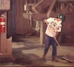 Worker sweeping floors in a fiberboard manufacturing facility