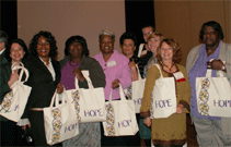 Representatives from the University of North Carolina Center for Health Promotion and Disease Prevention show off their Threads of HOPE bags at the Prevention Research Centers meeting in March 2008. The bags are made of sustainable materials and produced by rural North Carolina women.