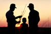 Two men and a child silhouetted in the sunset on a family farm.