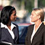 [PHOTOGRAPH] Black and white businesswomen smiling and talking to each other