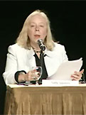 [PHOTOGRAPH] Sally Squires in front of a microphone, moderating the panel discussion