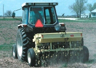 Photo of a farm tractor planting seed on a field.