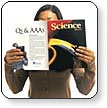 A woman reading Science magazine, holding the journal open in front of her. The heading "Qs and AAAS" is visible on the back cover.