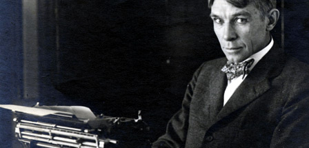 a young Carl Sandburg sitting behind his Remington typewriter wearing a dress coat and bow tie