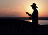 A picture of a farmer standing in front of a watershed at sunset