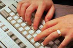 Photograph of hands typing on a keyboard.
