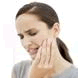 Photo of a woman holding one hand to her face and grimacing in pain
