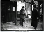 A man stands in front of a storefront window with posters announcing: Buy WSS; Peace plans have made little progress.