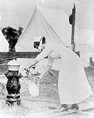 A nurse in a white uniform pumps water into a pitcher.