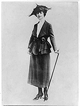 A black and white image of a fashionable woman holding a walking stick.