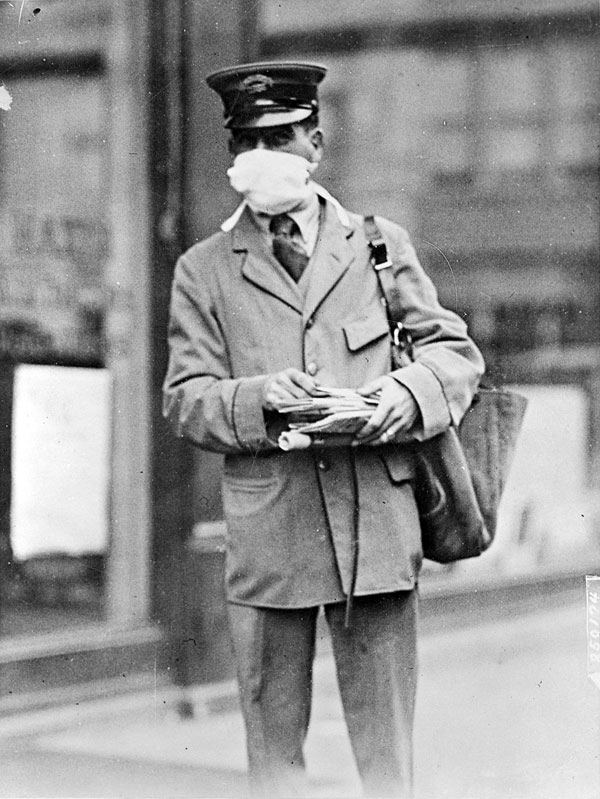 A New York mailman wears a mask covering his mouth and nose while delivering mail.   