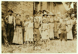 A group of mill workers mostly women and young girls standing in front of a building on the Mill grounds.
